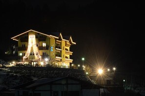 A multi-story building with balconies and a lit facade at night. - Hotel Al Lago (Folgaria)