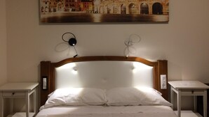 A hotel room with a bed, two bedside tables, a headboard with built-in lighting, and a wall-mounted painting of a historic building. - B&B Al 16 (Legnago)