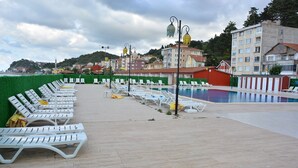 Zona de piscina con sillas reclinables blancas y una alberca.