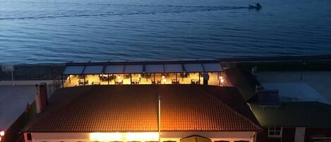 Un edificio con tejado de baldosas, un espacio de estar al aire libre cubierto y vistas al mar.