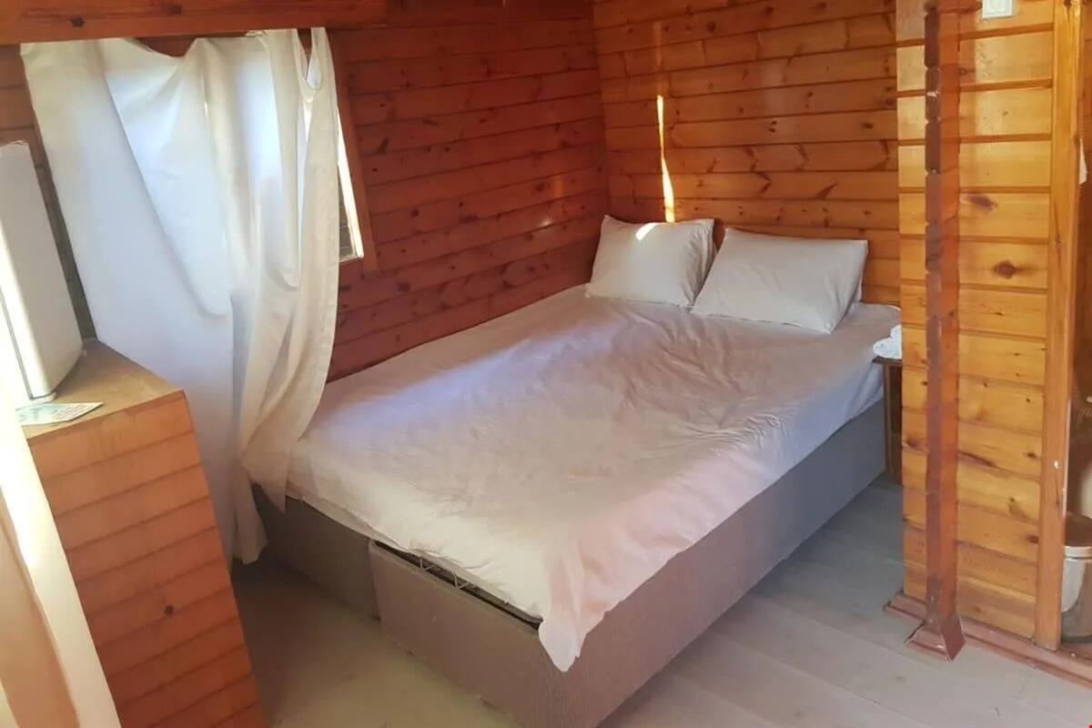 Une chambre dans une cabane en bois, avec un lit, des rideaux et un plancher en bois.