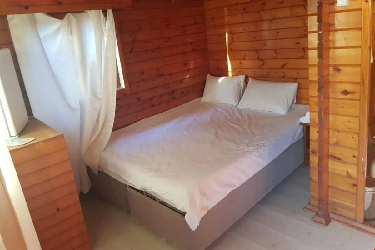 Une chambre dans une cabane en bois, avec un lit, des rideaux et un plancher en bois.