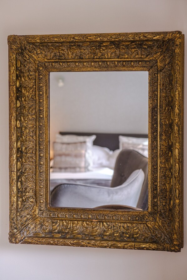 A mirror with an ornate gold frame reflecting a bed with pillows and a chair. - White Hart Cafe Bar & Bistro (Telford)