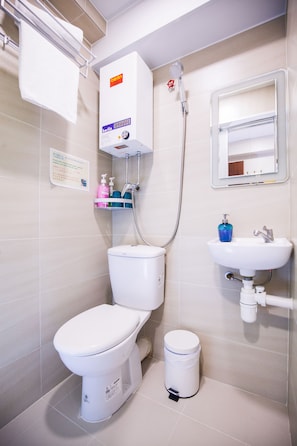A bathroom with a toilet, a sink, a shower, and a trash bin. - HK International Hostel (Kowloon)