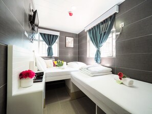 A modern hotel room with a bed, bedside table, and a small desk area. - HK International Hostel (Kowloon)