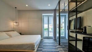 A modern hotel room with a large bed, a TV, and a balcony with a view. - Hotiday Olbia Wallure (Olbia)
