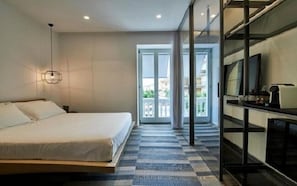 A modern hotel room with a large bed, a TV, and a balcony with a view. - Hotiday Olbia Wallure (Olbia)
