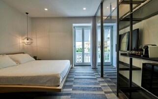 A modern hotel room with a large bed, a TV, and a balcony with a view.
