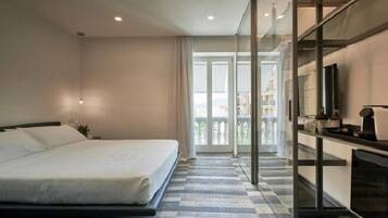 Una habitación de hotel con cama, televisión, balcón y mostrador de recepción.