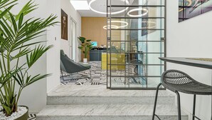 A modern interior with a geometric patterned floor, a glass partition, a desk, and a chair. - Hotiday Olbia Wallure (Olbia)