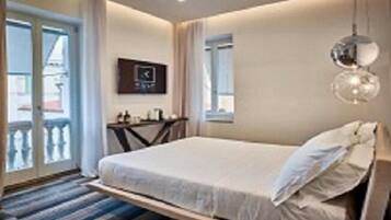 Une chambre d’hôtel avec un lit, une petite table, une chaise, une fenêtre et un balcon.