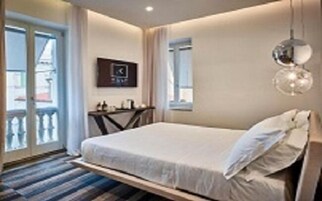 Ein Hotelzimmer mit Bett, einem kleinen Tisch, einem Sessel, einem Fenster und einem Balkon.