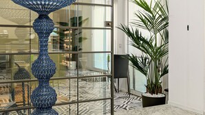 A modern interior with a large blue decorative lamp, a patterned floor, and a glass partition. - Hotiday Olbia Wallure (Olbia)