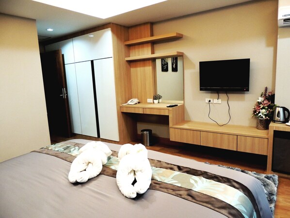 Una habitación de hotel con cama, escritorio, televisor y armario.