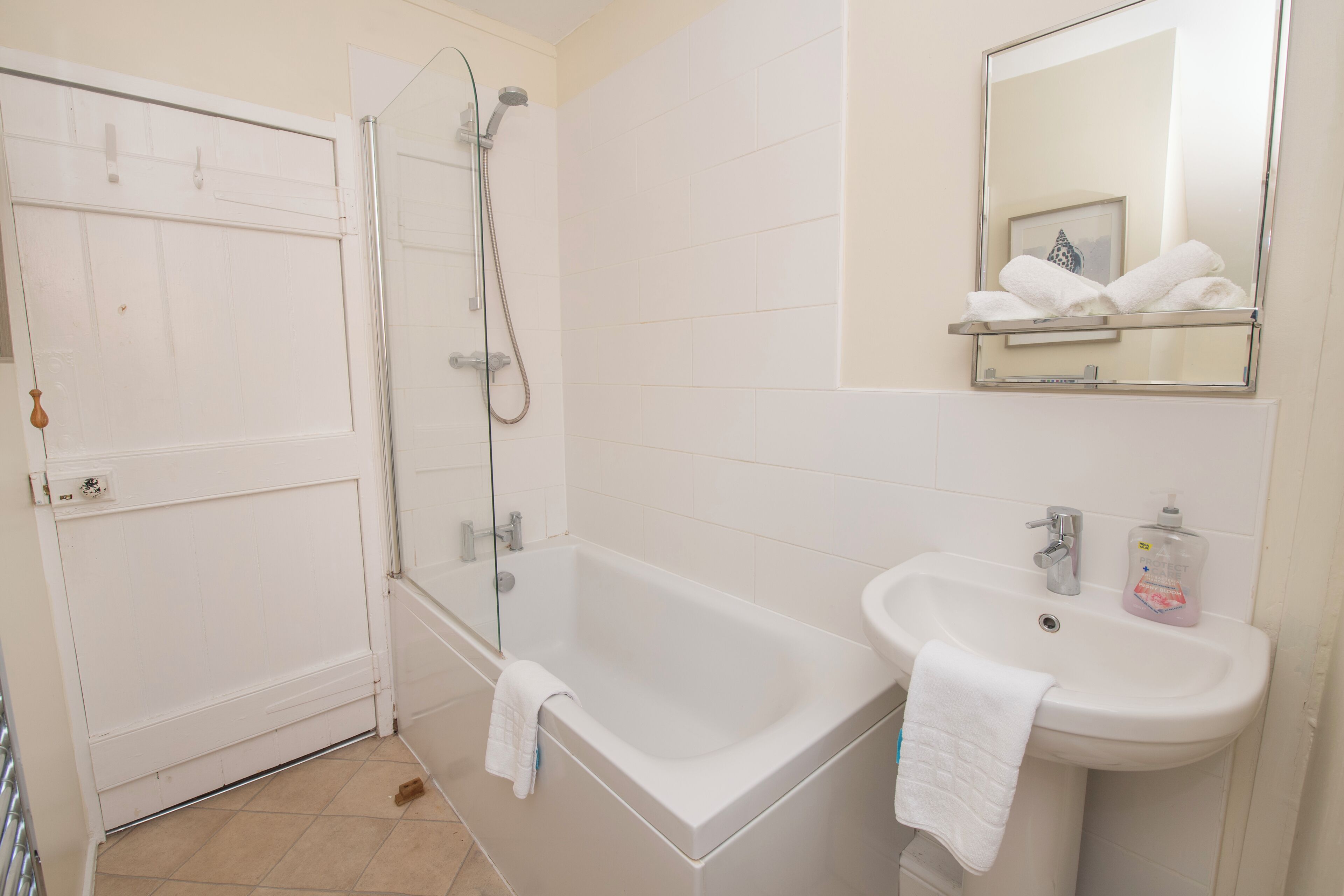 A bathroom with a bathtub, a sink, a shower, and a mirror.