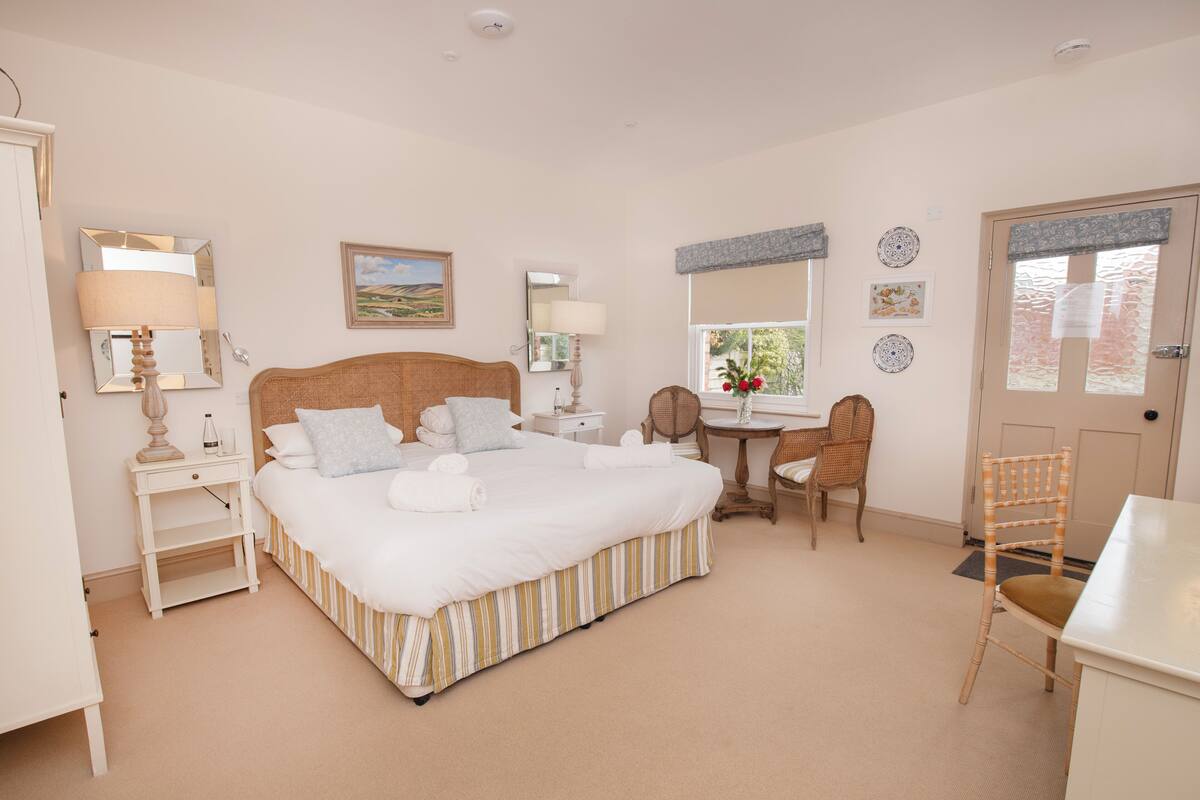 Ein Schlafzimmer mit einem großen Bett, Nachttischen, einem Schreibtisch und einem Stuhl.