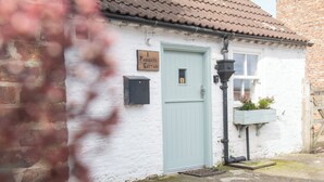 Ein Cottage mit einer hellblauen Tür, einem Schild darüber, einem Briefkasten und einem Blumenkasten.