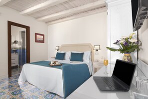 Ein Hotelzimmer mit einem Bett, einem Laptop auf einem Tisch, einer Blumenvase und einem Glas Orangensaft.