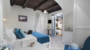 Une chambre d’hôtel avec un lit, un bureau avec un ordinateur portable, une petite table avec une plante et une vue sur l’extérieur.