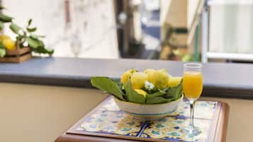 Un bouquet de fleurs jaunes dans un vase, posé sur une table, à côté d’un verre de jus d’orange.