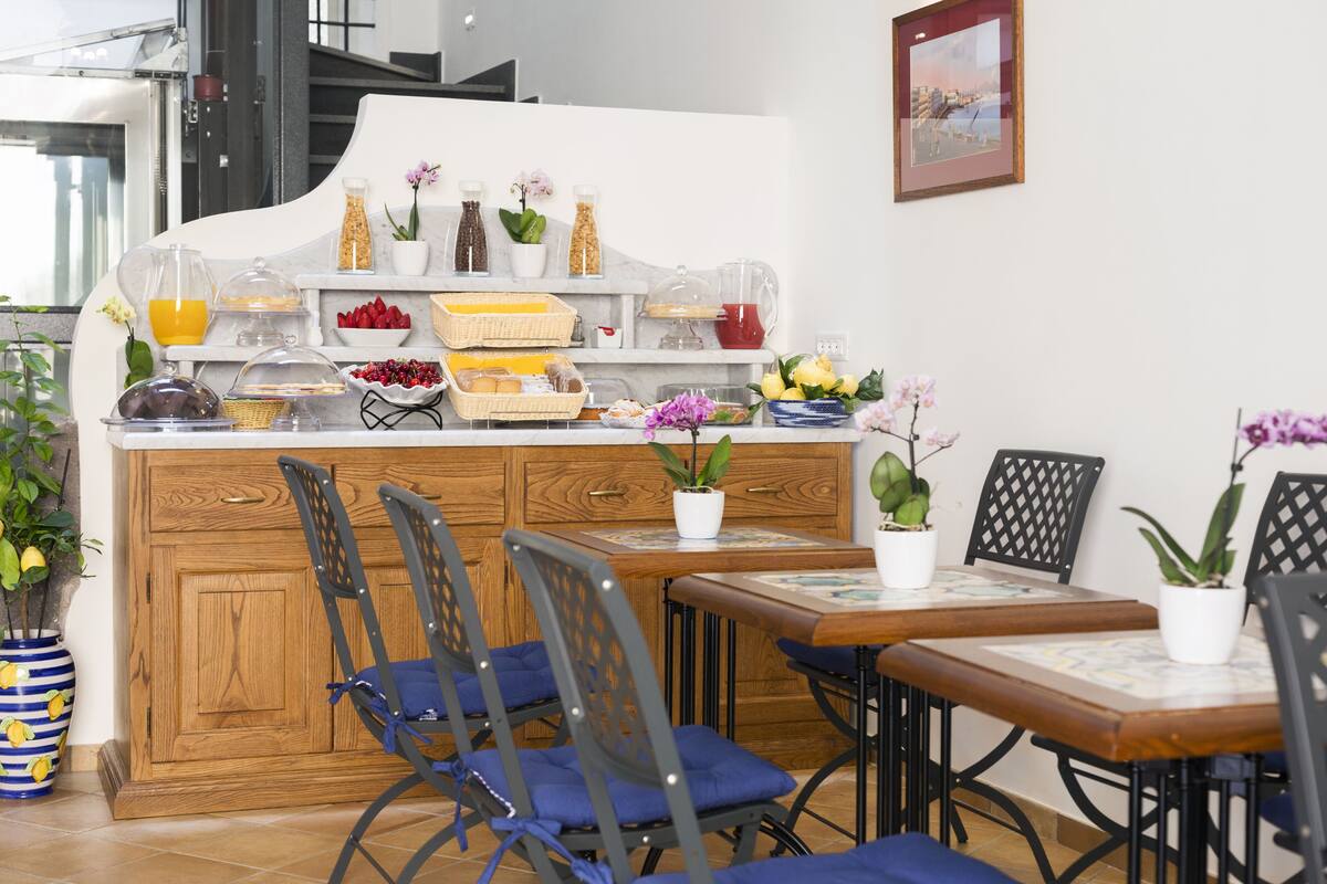 Un buffet pour le petit-déjeuner proposant une variété d’aliments et de boissons, entouré de chaises et de plantes en pot.