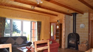 A cozy living room with a fireplace, wooden furniture, and a clock on the wall. - Whispering Spirit Holiday Cottages (Franklin)