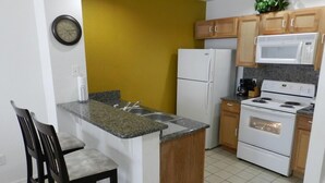 A compact kitchen with a built-in island, a refrigerator, a microwave, and a stove.