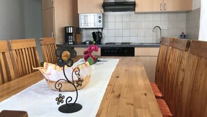 A modern kitchen with wooden cabinets, a gas stove, and a microwave. - Gästehaus am Bach - Ferienwohnungen (Rust)