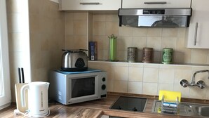 A modern kitchen with a microwave, toaster, kettle, and oven. - Gästehaus am Bach - Ferienwohnungen (Rust)