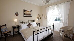 A neatly arranged bedroom with a bed, bedside tables, a chair, and a window with curtains. - Byrness House (Newcastle-upon-Tyne)