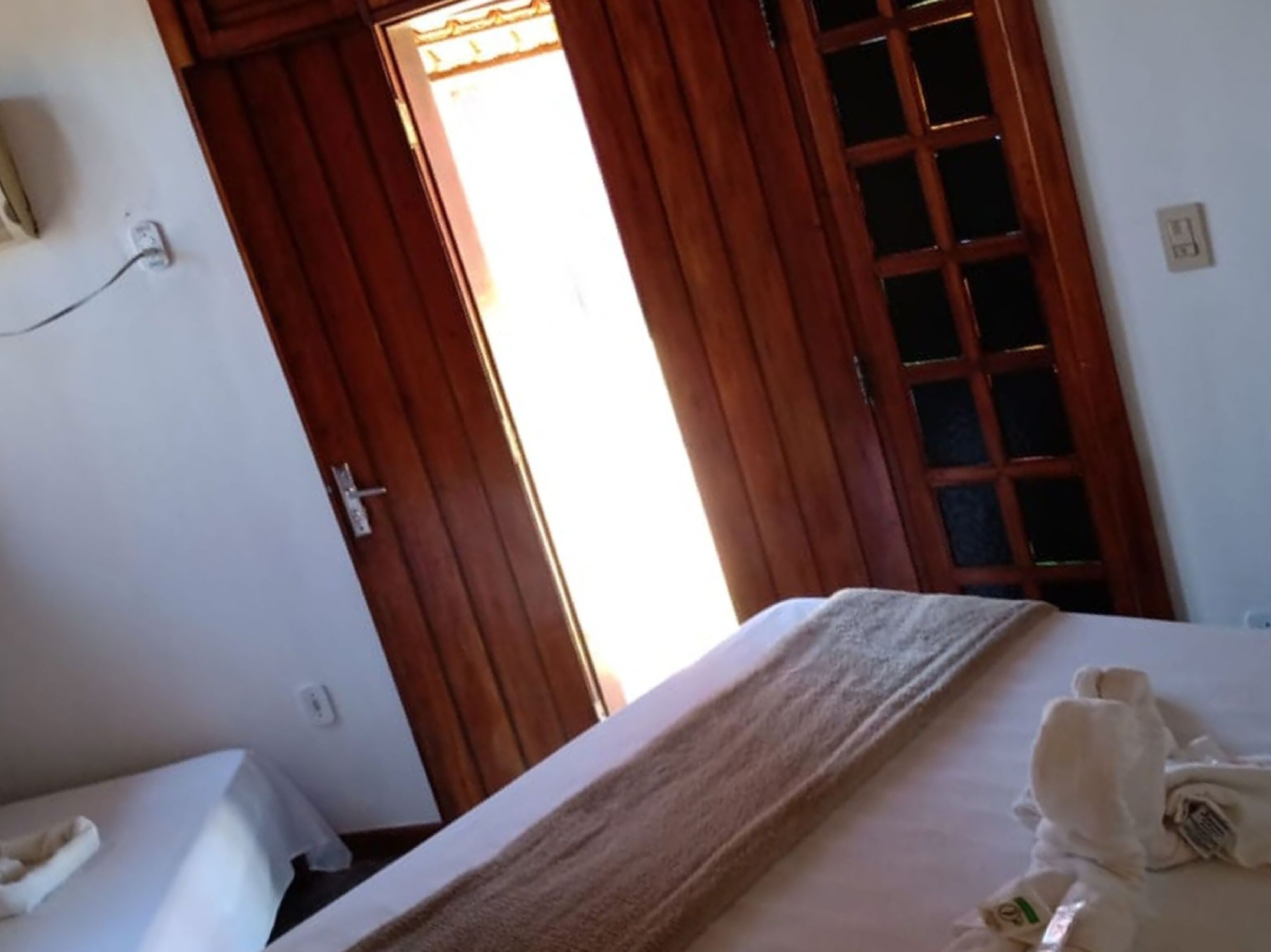A hotel room with a bed, a wooden door, and a white wall.