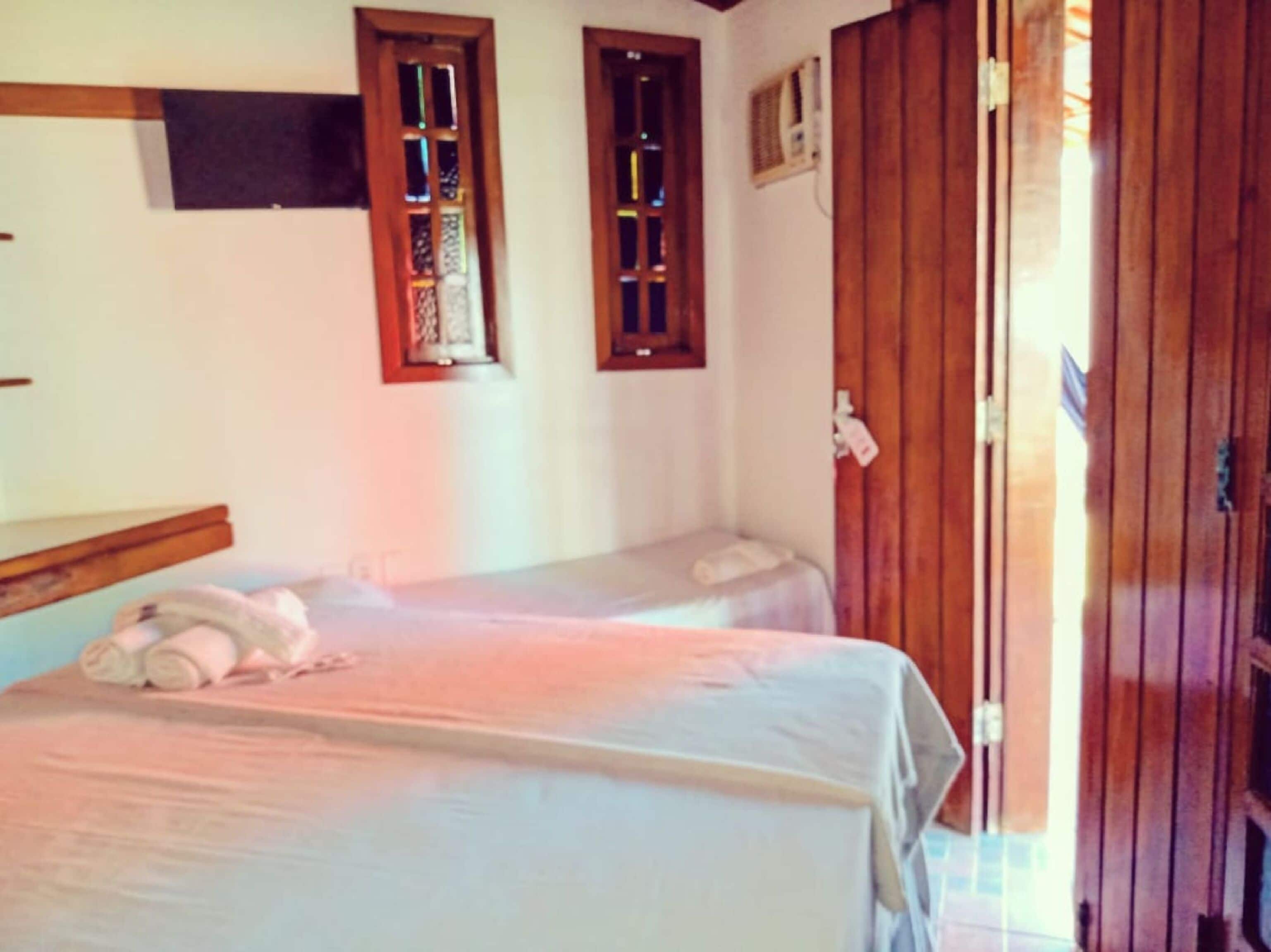 A room with two single beds, wooden doors, and a small window with a decorative frame.