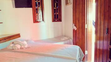 A room with two single beds, wooden doors, and a small window with a decorative frame.