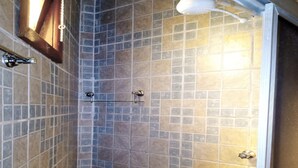 Une douche avec une porte en verre et un porte-serviettes en métal.