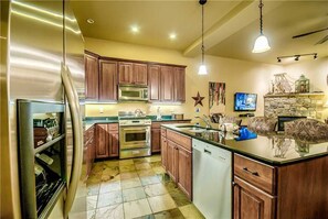 Een kookplaat, een vaatwasser, kookgerei, borden en bestek, eettafels