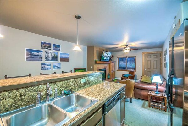 Een kookplaat, een vaatwasser, kookgerei, borden en bestek, eettafels