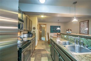 Een kookplaat, een vaatwasser, kookgerei, borden en bestek, eettafels