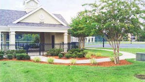 A building with a covered entrance, a number "2201" on the roof, and a landscaped front yard with a tree and shrubs.