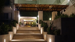 A staircase leading to a building entrance with a wooden overhang and potted plants on either side. - Ocean Dream 1 Bedroom Condo (Cancun)