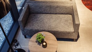 Een modern interieur met een bank, twee kleine tafels en een groot raam.