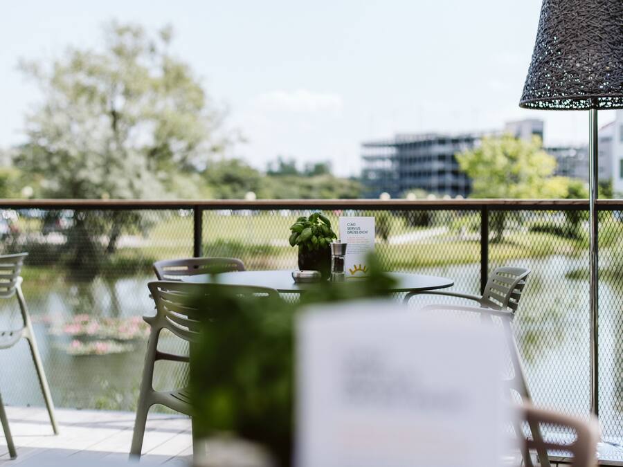 An outdoor dining area with a table and chairs, a small plant, and a sign.