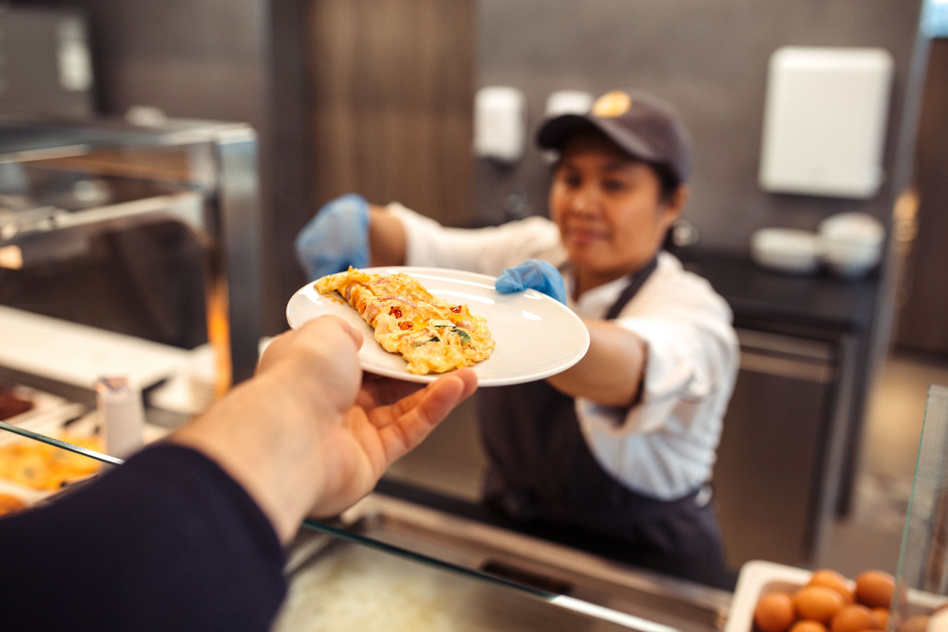 Una persona entrega un plato de comida a un camarero en un restaurante.