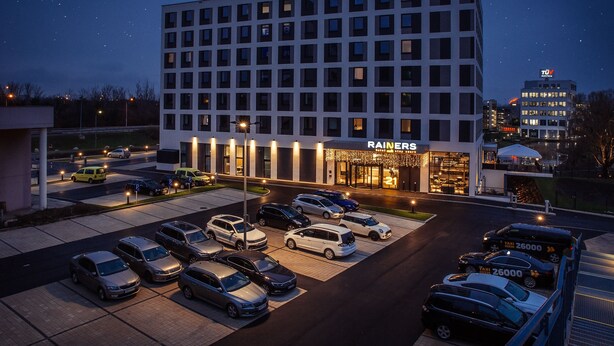 Een hotel met een modern design, meerdere parkeerplaatsen en een goed verlichte entree.