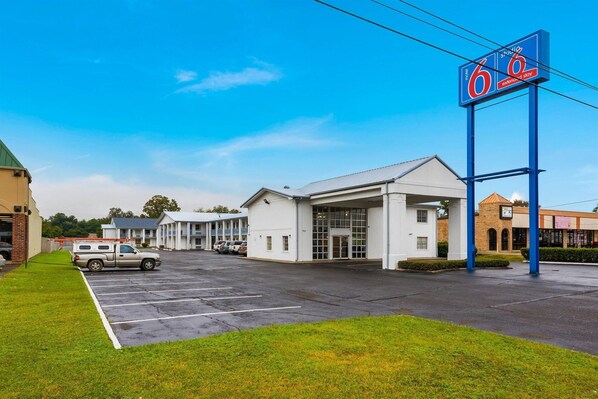 Un motel con un letrero grande, un estacionamiento y un edificio de fachada blanca.