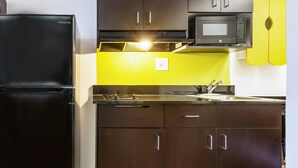 A compact kitchen with a black refrigerator, a microwave, and a sink. - Studio 6 Alexandria, LA (Alexandria)