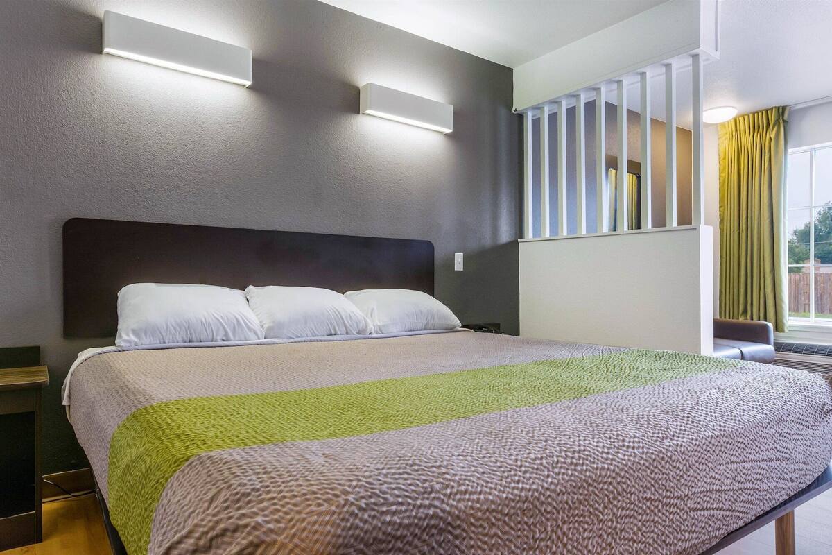A modern hotel room with a large bed, a headboard, and built-in lighting.