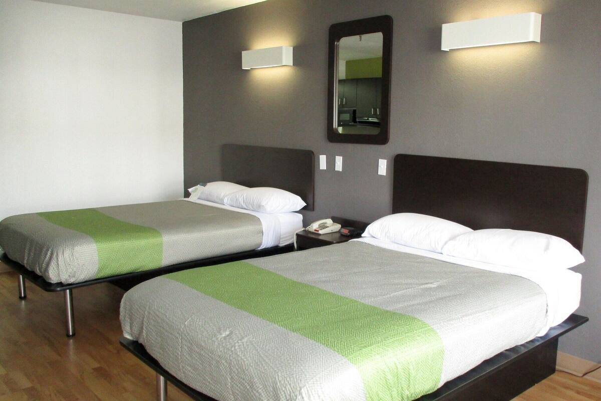 Two twin beds with green and white bedding, a bedside telephone, and a wall-mounted mirror.