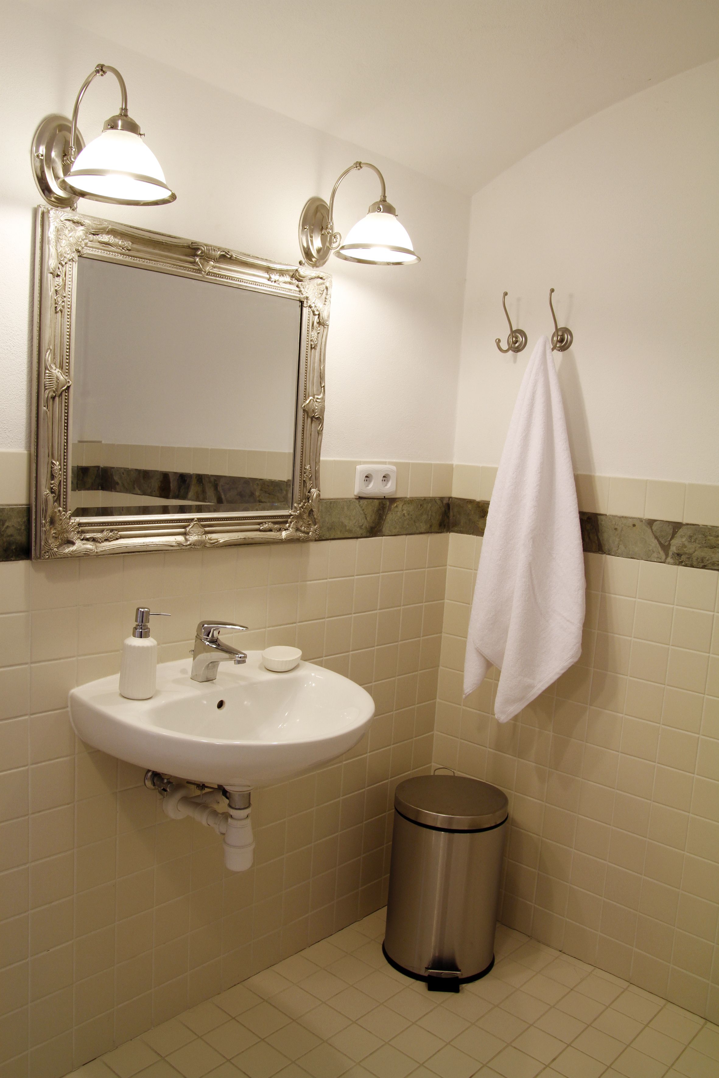 Ein Badezimmer mit Waschbecken, Spiegel, Handtuchhalter und Mülleimer.