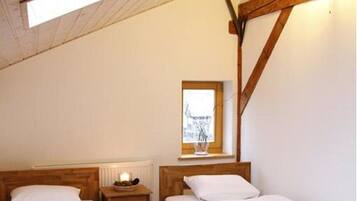 Una habitación con dos camas de madera, techo de madera y tragaluz.