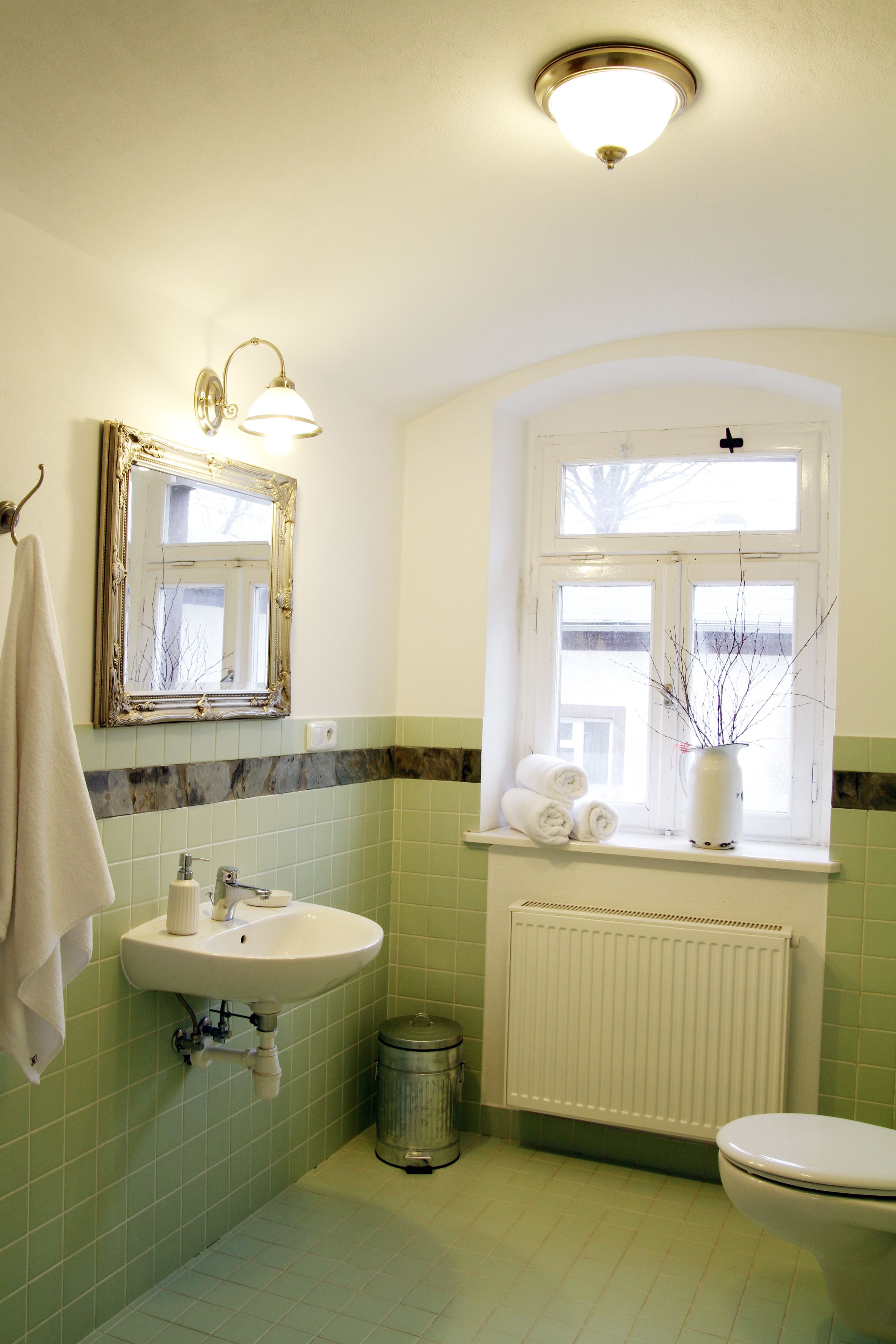Une salle de bain avec un lavabo, un miroir, une fenêtre et des toilettes.